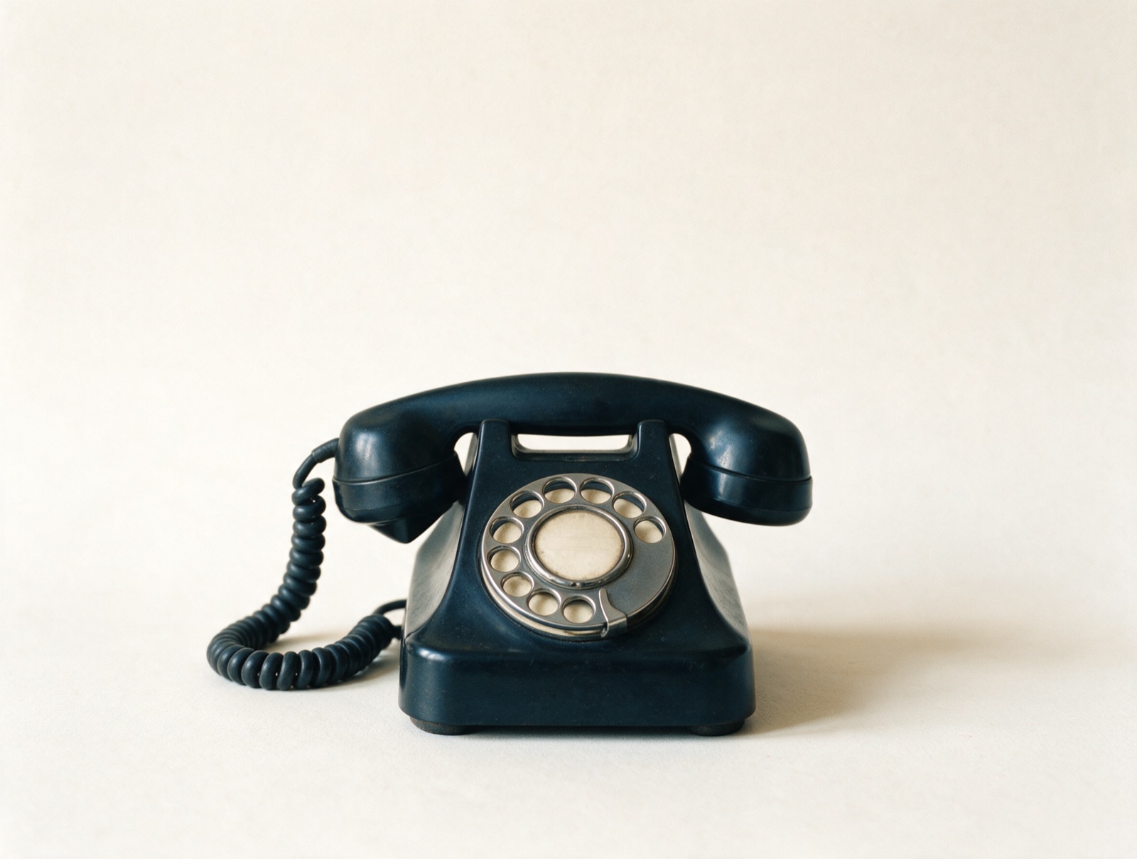 Klassisches dunkelblaues Telefon mit Wählscheibe vor hellem Hintergrund